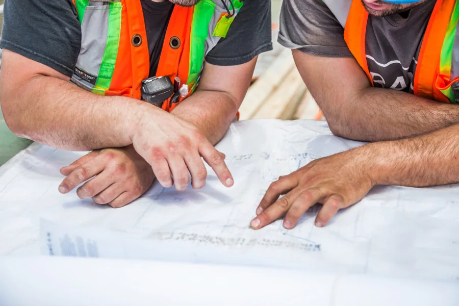 Builders in high-visibility vests reviewing plans on a table