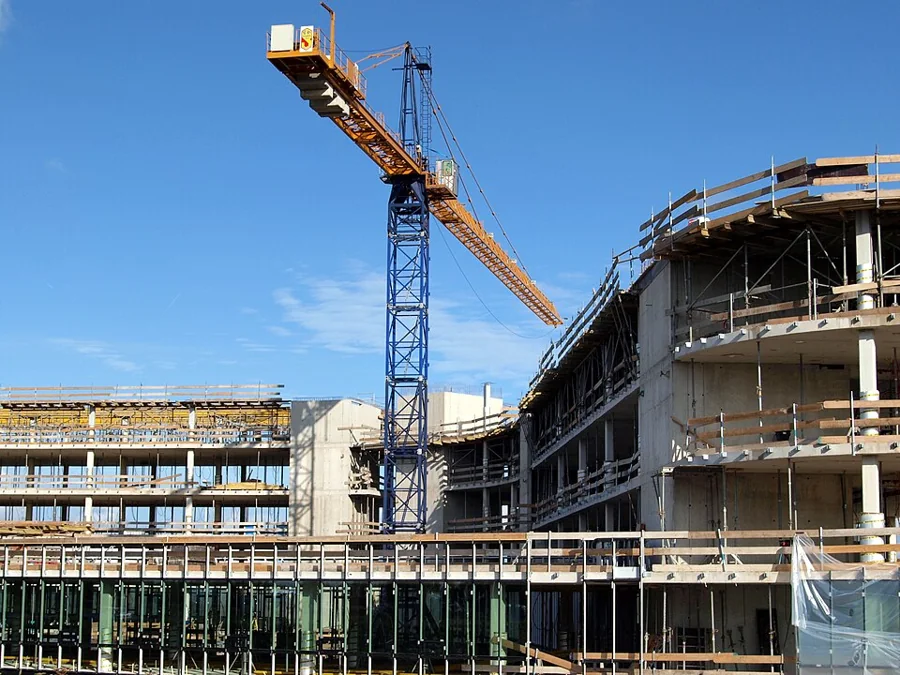 A multi-storey building rising beside a tower crane